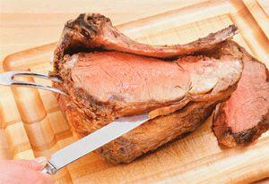 Вареното свинско месо се измъкна от бавната готварска печка и се нарязва с нож