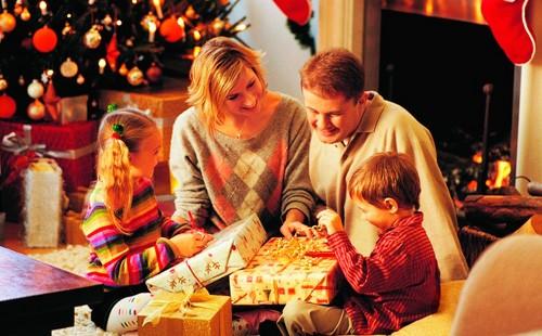 Lapset pakkaavat lahjat lähellä joulukuusi vanhempiensa kanssa