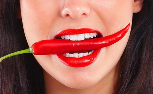 Dívka se snaží jíst červené papriky