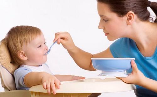 La giovane madre nutre suo figlio da un cucchiaio
