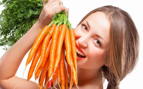 Fröhliches Mädchen hält eine ganze Reihe von Karotten