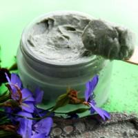 Argila negra en un pot de vidre entre violetes
