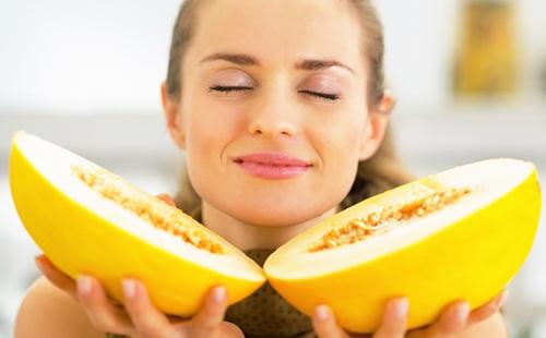 Mädchen genießt den Geruch einer in zwei Hälften geschnittenen Melone