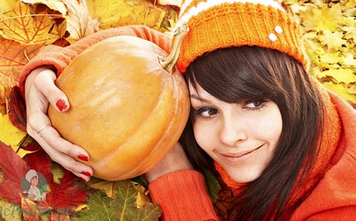Mädchen in einer orangefarbenen Mütze umarmt die Früchte des Herbstes