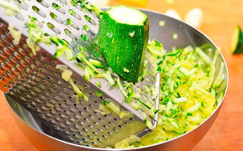 Strofinando le zucchine su una grattugia grossa