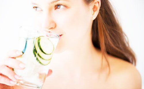 Meisje drinkt water met komkommers