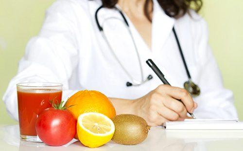 Früchte liegen auf einem Tisch vor einem Doktor, der etwas schreibt