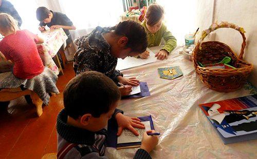 Kinder sitzen am Tisch und malen
