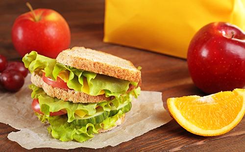 Sandwich avec salade verte, tranche d'orange et pommes rouges au petit déjeuner