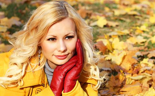 Блондинката в червени ръкавици сред есенната зеленина