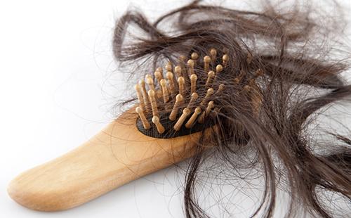 Un mucchio di capelli tra i denti di una spazzola di legno