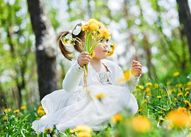 Dívka v bílých šatech drží kytici pampelišek