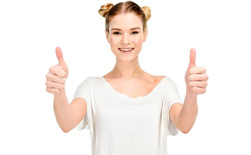 Радостно момиче в бяла тениска показва палци нагоре