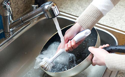امرأة تغسل مقلاة