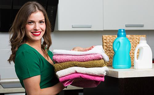 Zufriedene Hausfrau mit einem Stapel sauberer Wäsche