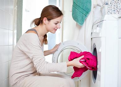 Nő piros vörös pulóvert helyez a mosógépbe