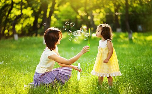 Mama ir dukra žaidžia su muilo burbuliukais