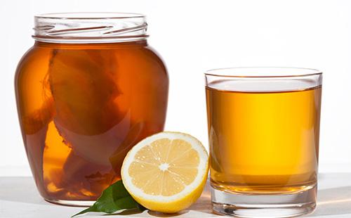 Kombucha v pohári, citróne a hrnku s čajom