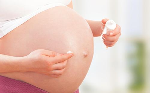 La donna incinta applica la crema sulla pancia