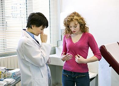 Dívka u doktorova jmenování ukazuje na její žaludek