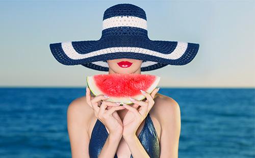 Das Mädchen mit dem Hut hält eine Scheibe Wassermelone in der Hand