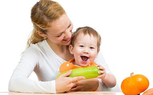 Madre con bambino al tavolo tenere zucchine