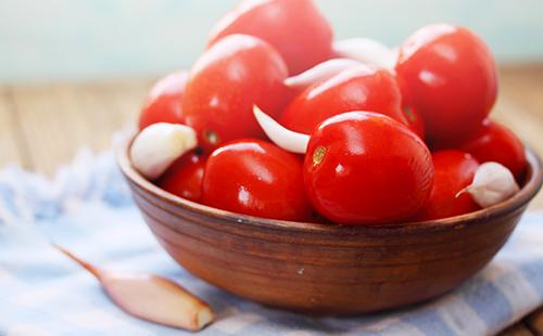 Tomaten mit Knoblauch in einer hölzernen Schale
