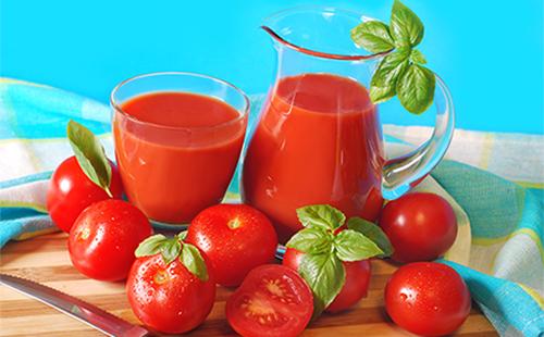 عصير طماطم في إبريق وزجاج وطماطم وأعشاب