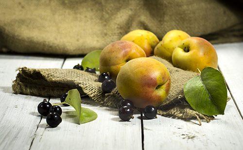 Aprikosen und Schwarze Johannisbeeren auf einem Holztisch
