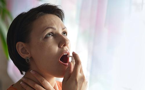 Une femme fourre un médicament dans sa bouche