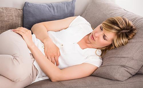 Mädchen mit Bauchschmerzen auf der Couch liegen