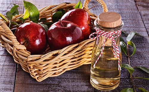 Omenasiideri etikka ja punaiset omenat korissa