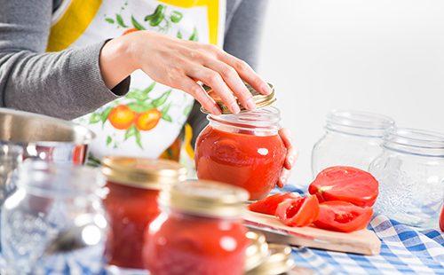 Nainen täyttää purkit tomaattikastikkeella