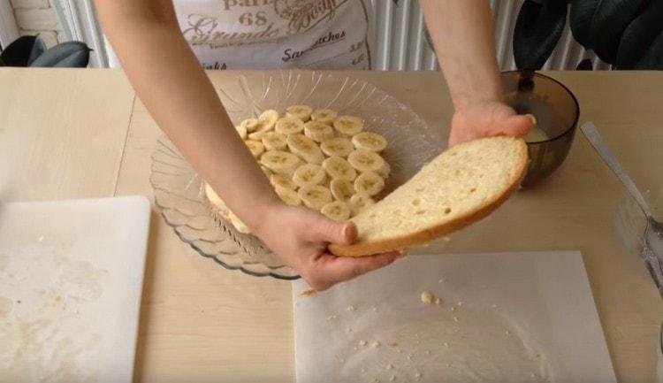 Τοποθετήστε ένα στρώμα μπανάνας στο κάτω κέικ και καλύψτε το με ένα δευτερόλεπτο.