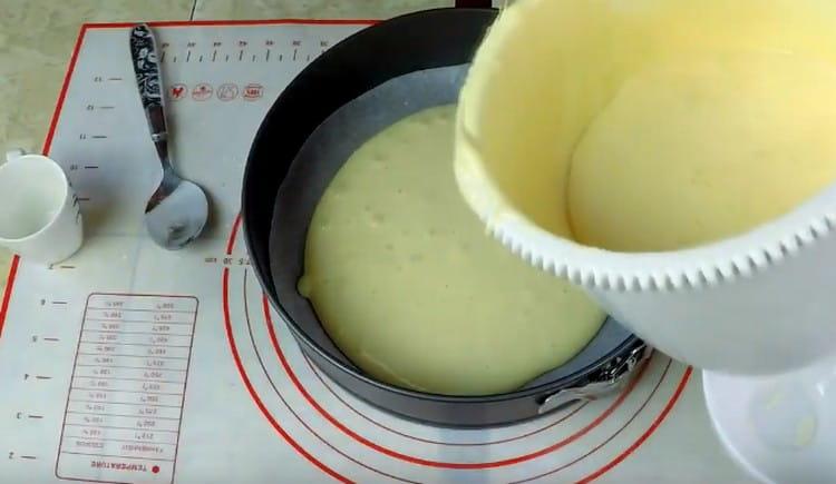 A sütőedény alját pergamennel fedjük le, és a benne lévő tészta felét egyenletes réteggel osztjuk el.
