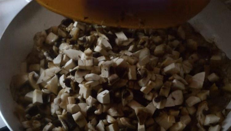 Friggere i funghi con le cipolle in una padella fino a cottura.