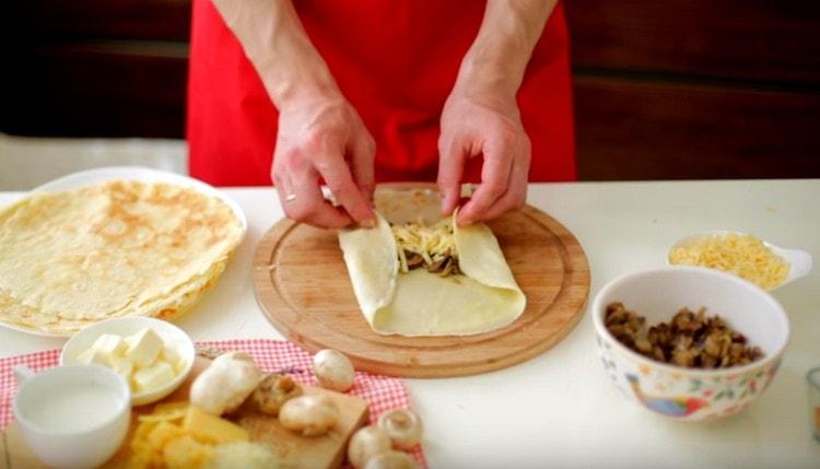 Τυλίγετε τηγανίτες με μανιτάρια και τυρί σε φακέλους.