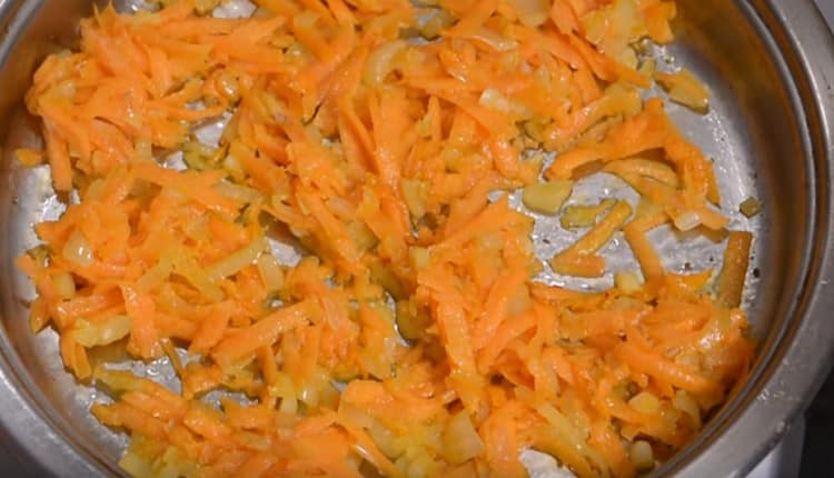 Zwiebeln mit Karotten in einer Pfanne mit Pflanzenöl anbraten.