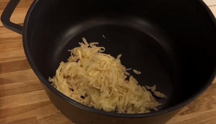 صر البطاطس ووضعها في وعاء عميق لطهي اللحم المفروم.