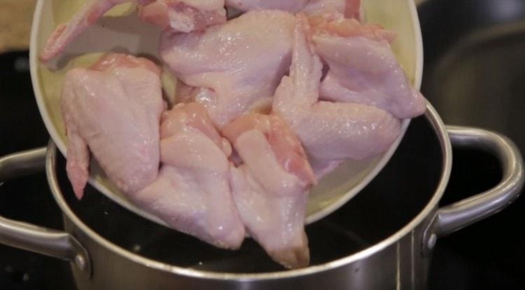 Στο τηγάνι με νερό, βάλτε τα φτερά κοτόπουλου.