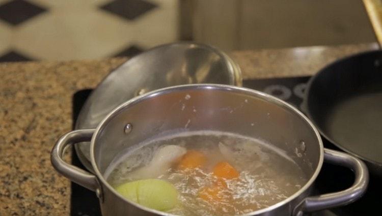Προσθέστε καρότα και κρεμμύδια στο ζεστό ζωμό.