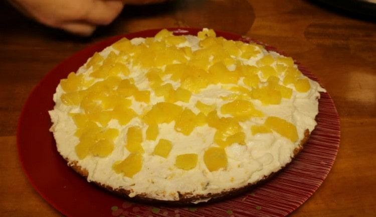 Den ersten Teil des Kuchens mit Sahne einfetten und mit Ananas bestreuen.
