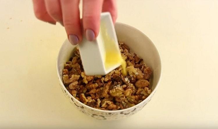 Изсипете сушените орехи в тиган с разтопено масло.