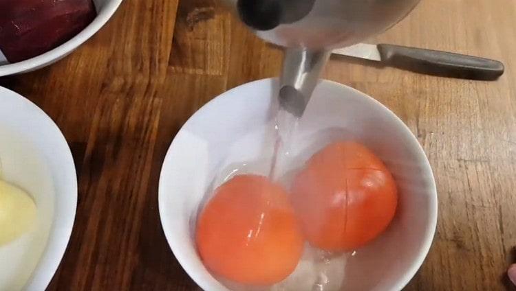 Wir schneiden die Tomaten ein und füllen sie mit kochendem Wasser.