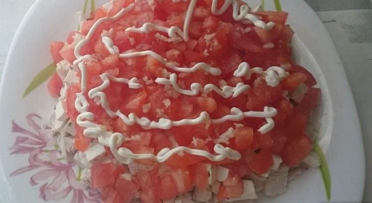 Wir verteilen die Tomate auf der Käseschicht, bestreuen sie mit gehacktem Knoblauch und machen ein Mayonnaisennetz.