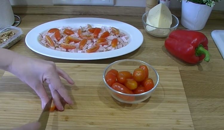 Tagliamo i pomodorini in quattro e li distribuiamo uniformemente sopra il pollo.