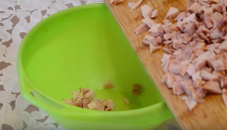 Wir schieben das gehackte Hühnerfleisch in eine tiefe Schüssel, die zum Mischen des Salats geeignet ist.