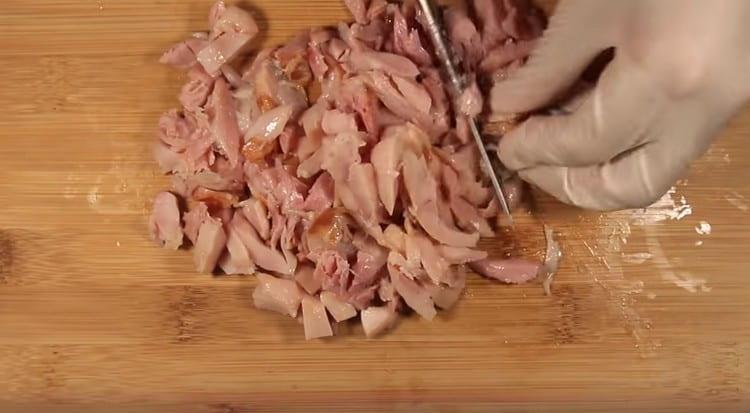 Wir entfernen die Haut von den Hähnchenschenkeln, schneiden das Fleisch in Stücke.