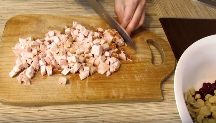 Taglia a dadini il filetto di pollo affumicato e passa agli ingredienti già preparati.