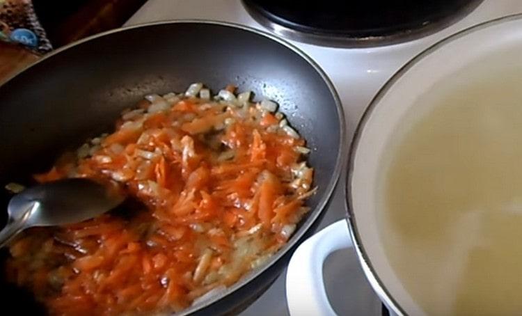 Fügen Sie der Zwiebel in der Pfanne Karotten hinzu und lassen Sie die Bratpfanne noch einige Minuten köcheln.